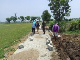 Babinsa Tanjunganom Bersama Warga Gotong Royong Pasang Paving Jalan di Desa Getas