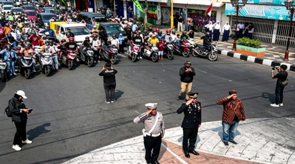 Para pengguna jalan bersama anggota Satlantas Polres Nganjuk menghentikan kendaraan dan memberikan penghormatan kepada Sang Saka Merah Putih di seputaran Pos Tugu Jayastamba, Jalan A. Yani, Nganjuk. (Ist/Zaki/SRTV)