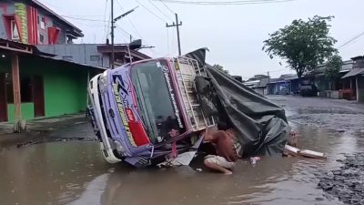 Rusak Parah, Jalan Arum Dalu Guyangan Jadi ‘Kolam’ Truk Muat Keramik Terguling